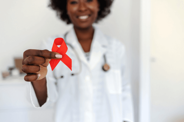 A doctor holding a red ribbon, symbolizing support for HIV/AIDS awareness.