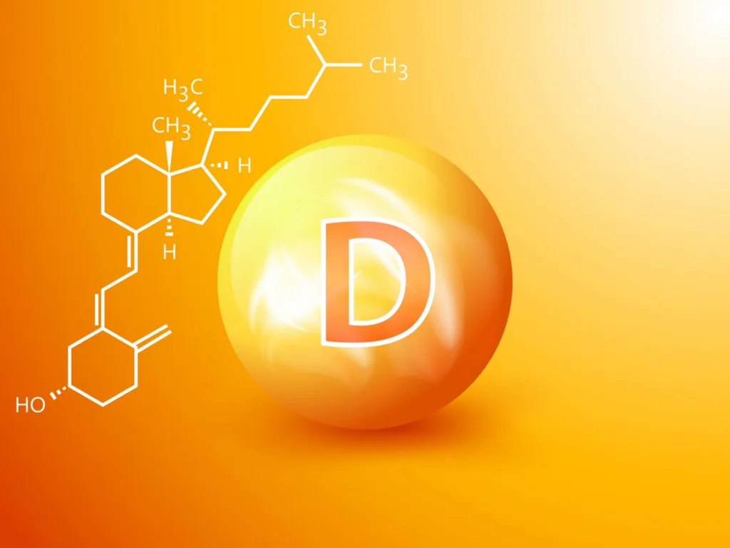 Uno sfondo arancione brillante mostra una grande e luminosa vitamina D con una "D" bianca al centro. A sinistra, è visualizzata una struttura molecolare dettagliata della vitamina D con vari legami chimici e atomi etichettati.