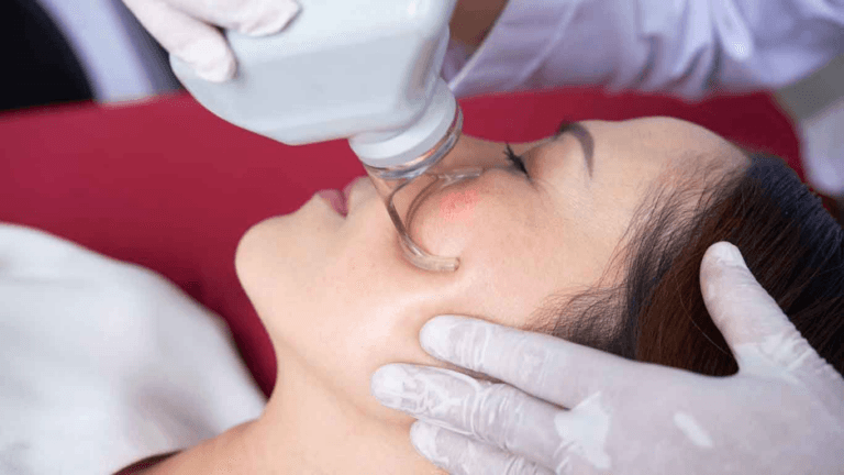 Врач проводит процедуру на лице пациента с использованием медицинского устройства.
