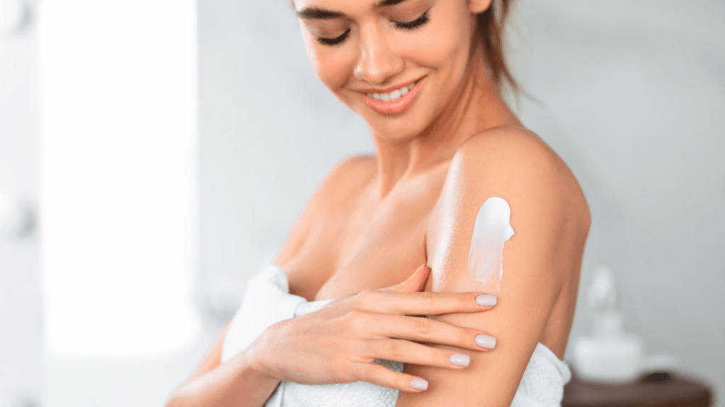 Una donna che si applica la crema sul braccio sorridendo.