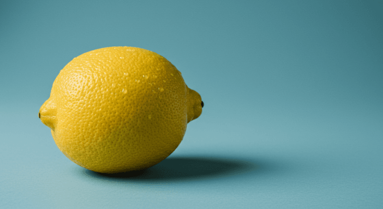 A bright yellow lemon is placed on a blue background, casting a small shadow to the right.