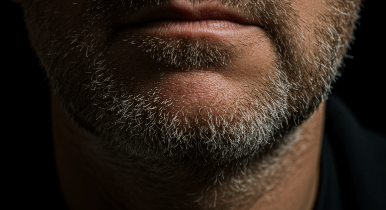 Eine Nahaufnahme des Gesichts eines Mannes mit Bart und Schnurrbart. Das Bild hebt die Textur und Details seiner Gesichtsbehaarung hervor.